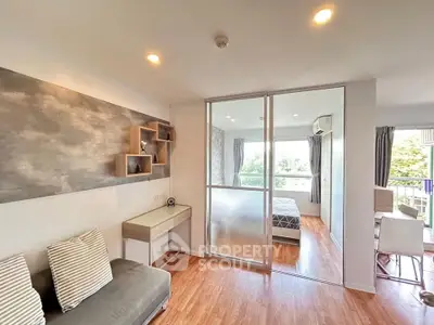 Modern apartment interior with stylish living room and cozy bedroom separated by glass partition.