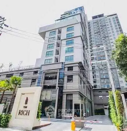 Modern high-rise condominium building with sleek design and lush greenery at entrance.