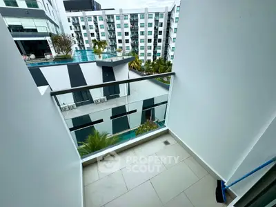 Modern apartment balcony with pool and building view, perfect for relaxation.