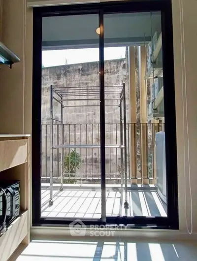 Modern apartment balcony with sliding glass door and laundry rack, perfect for urban living.