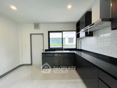 Modern kitchen with sleek black cabinets and large window