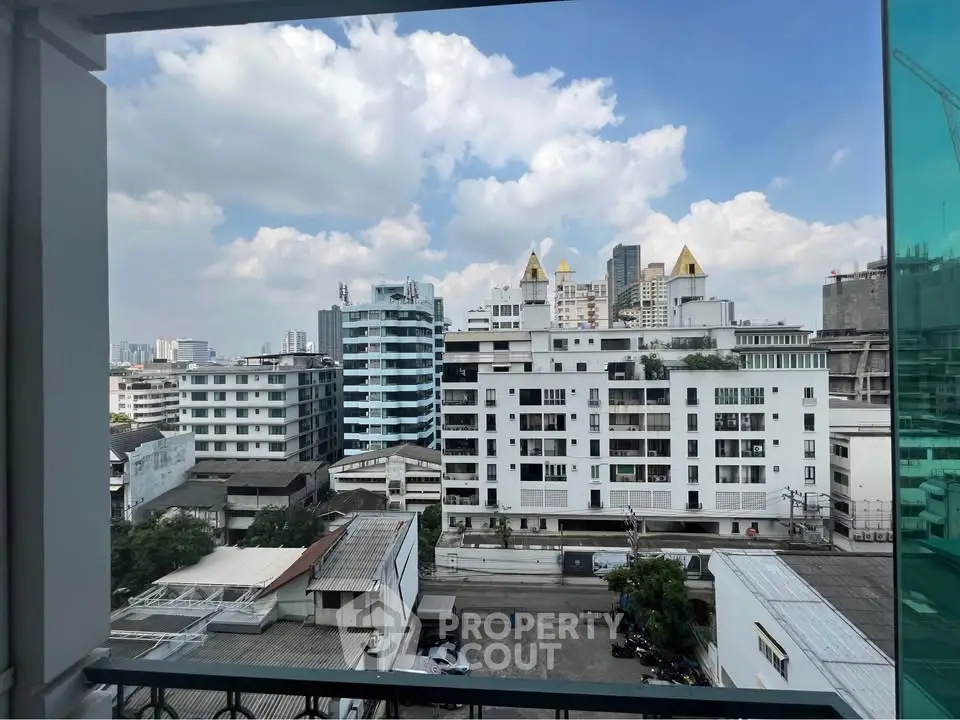 Stunning cityscape view from a modern apartment balcony with clear blue skies.