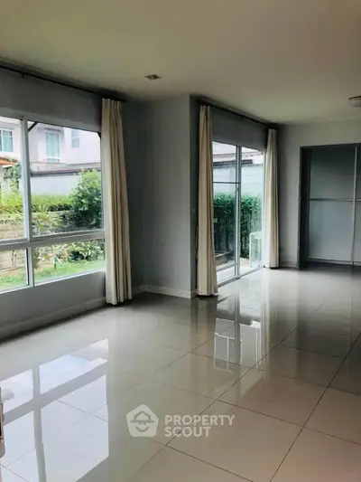 Spacious empty living room with large windows and garden view