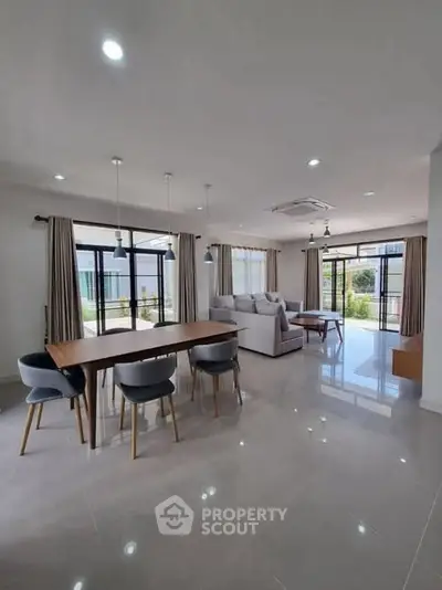 Spacious modern living room with elegant dining area and large windows for natural light.