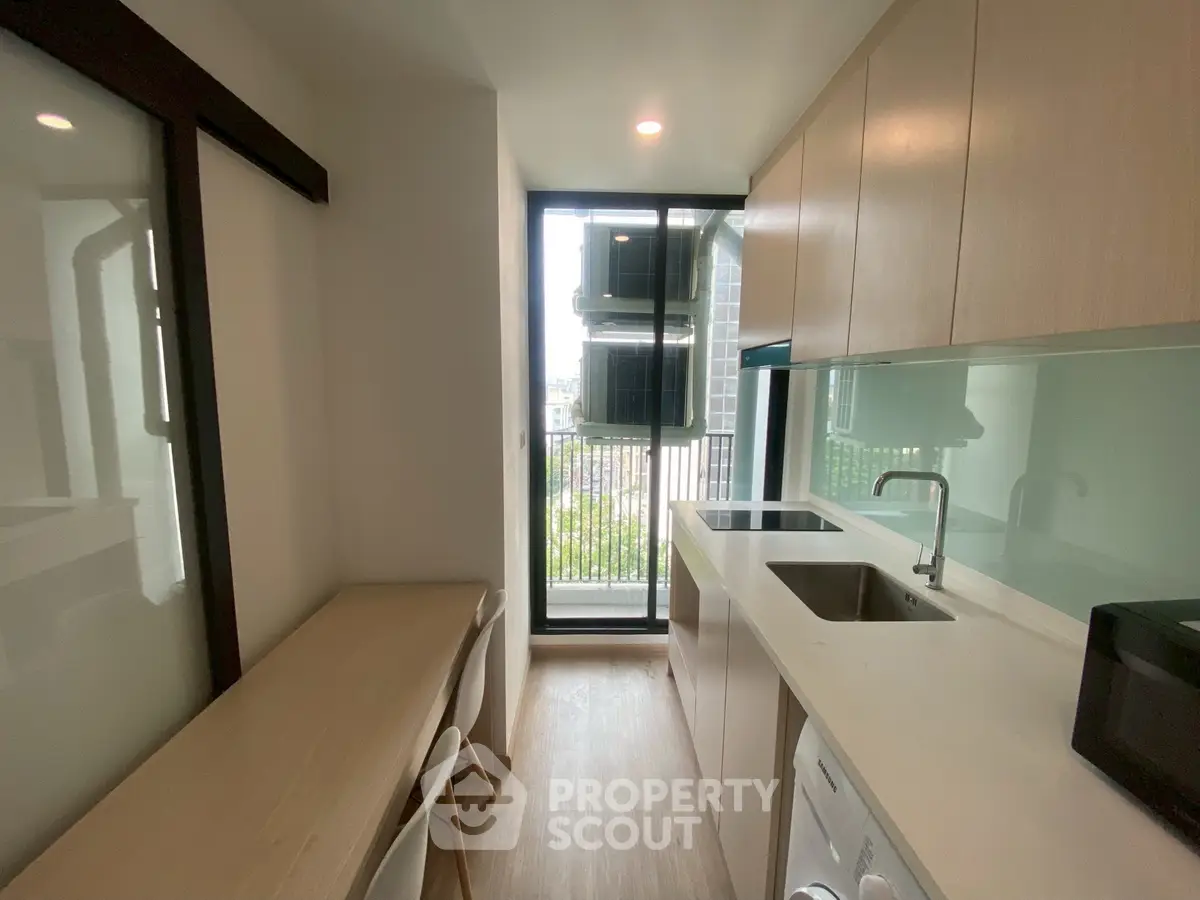 Modern kitchen with sleek design and natural light, featuring built-in appliances and a compact dining area.