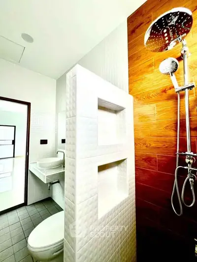 Modern bathroom with stylish shower and textured tiles, featuring a sleek sink and contemporary design.