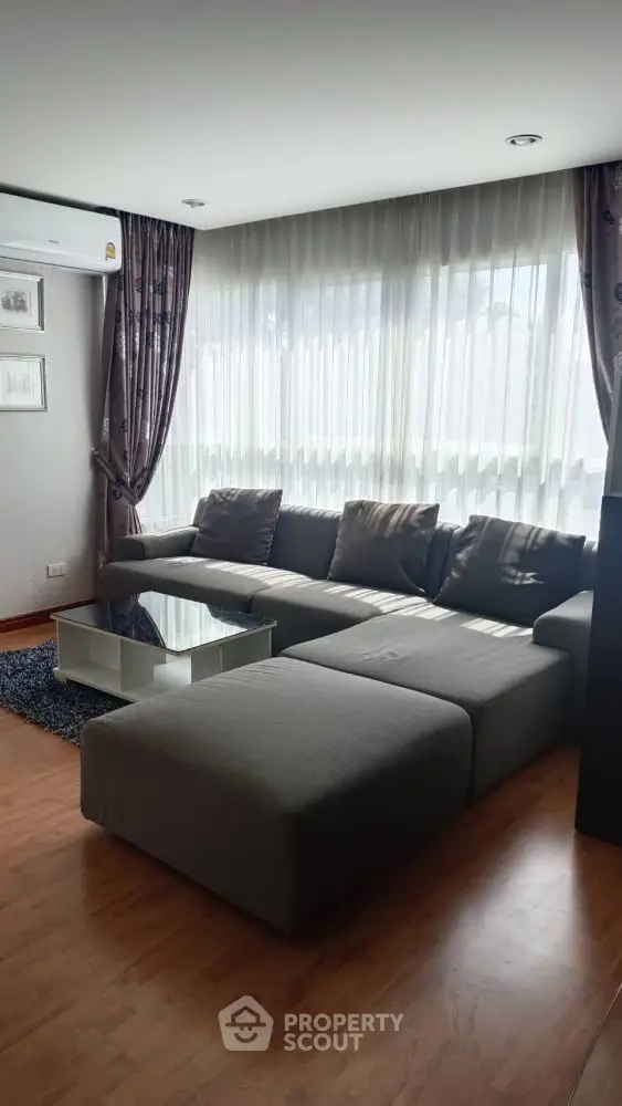 Stylish living room with modern gray sectional sofa and large windows.