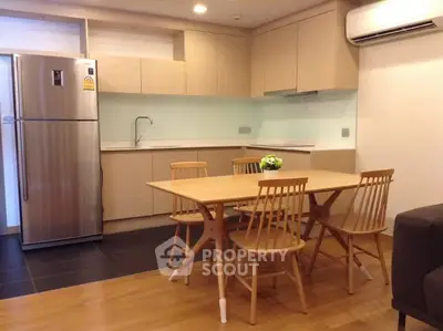 Modern kitchen with dining area and stainless steel fridge in cozy apartment.