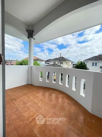 Spacious balcony with terracotta tiles and scenic neighborhood view.