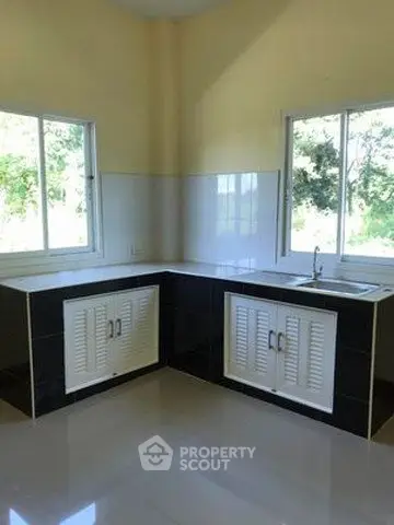 Modern kitchen with sleek black and white cabinetry and large windows offering natural light.