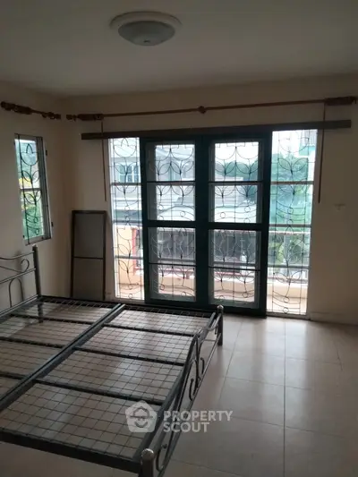 Spacious bedroom with large windows and balcony access in modern apartment.