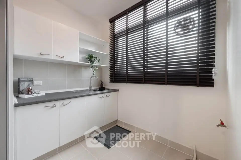Modern kitchen with sleek white cabinets and large window blinds