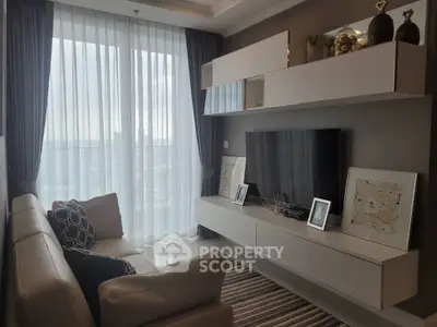 Modern living room with sleek furniture and large window offering natural light.