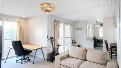 Spacious living room with exercise bike and modern kitchen in open layout apartment.