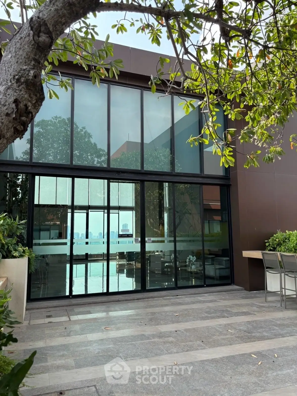Modern building exterior with large glass windows and lush greenery, offering a serene urban oasis.