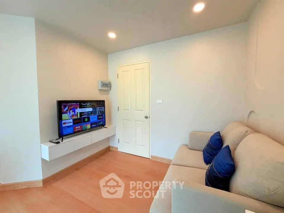 Modern living room with cozy sofa and wall-mounted TV in a bright apartment.