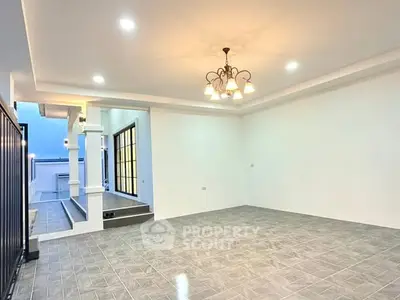 Spacious modern living room with elegant chandelier and tiled flooring.