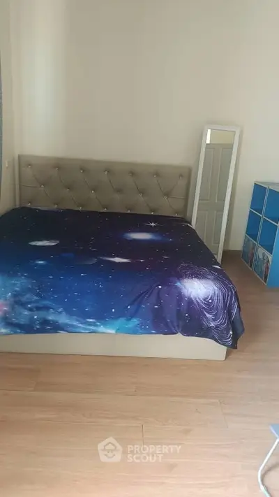 Spacious bedroom with galaxy-themed bedding and modern decor