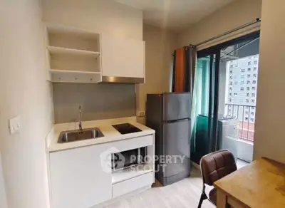 Modern compact kitchen with balcony access in urban apartment