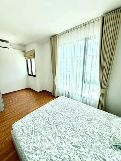 Bright and airy bedroom with large window and elegant curtains, perfect for relaxation.