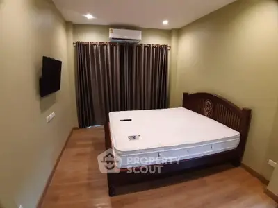 Cozy bedroom with wooden flooring, elegant bed, and air conditioning, perfect for relaxation.