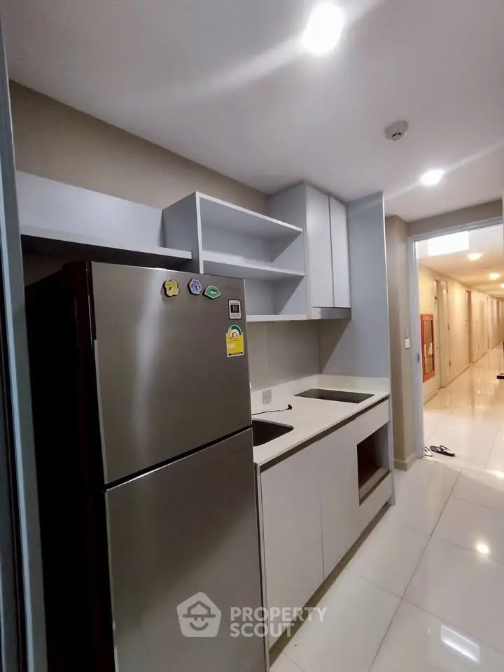 Modern kitchen with sleek cabinetry and stainless steel fridge in a contemporary apartment.