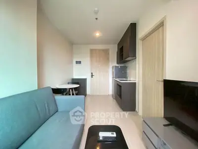Modern living room with sleek furniture and compact kitchen in open layout apartment.