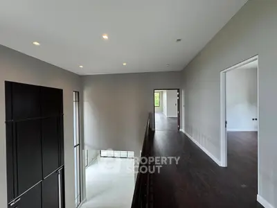 Spacious modern interior with high ceilings and elegant dark wood flooring.
