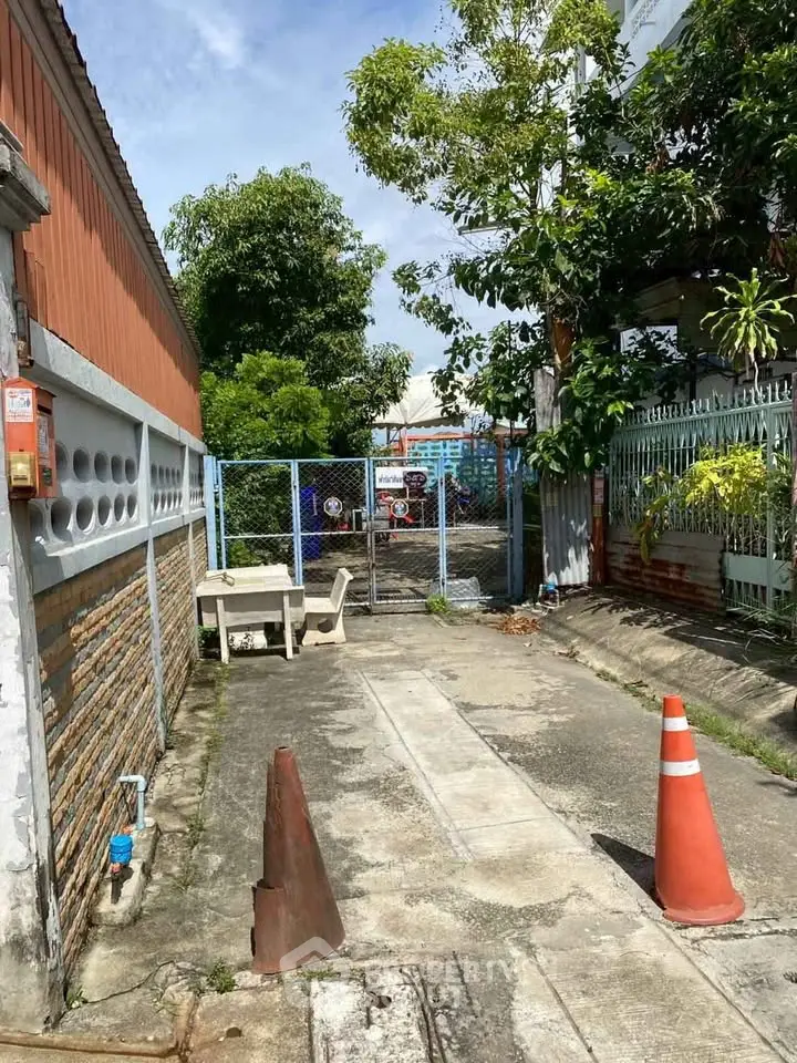 Charming gated entrance with lush greenery and paved pathway, perfect for urban living.