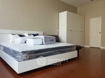 Spacious modern bedroom with sleek white furniture and wooden flooring