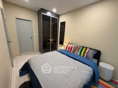 Cozy bedroom with modern decor and colorful accents, featuring a comfortable bed and sleek wardrobe.