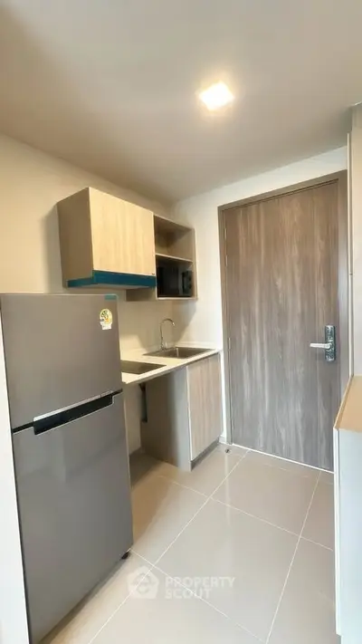 Modern compact kitchen with sleek cabinetry and stainless steel fridge