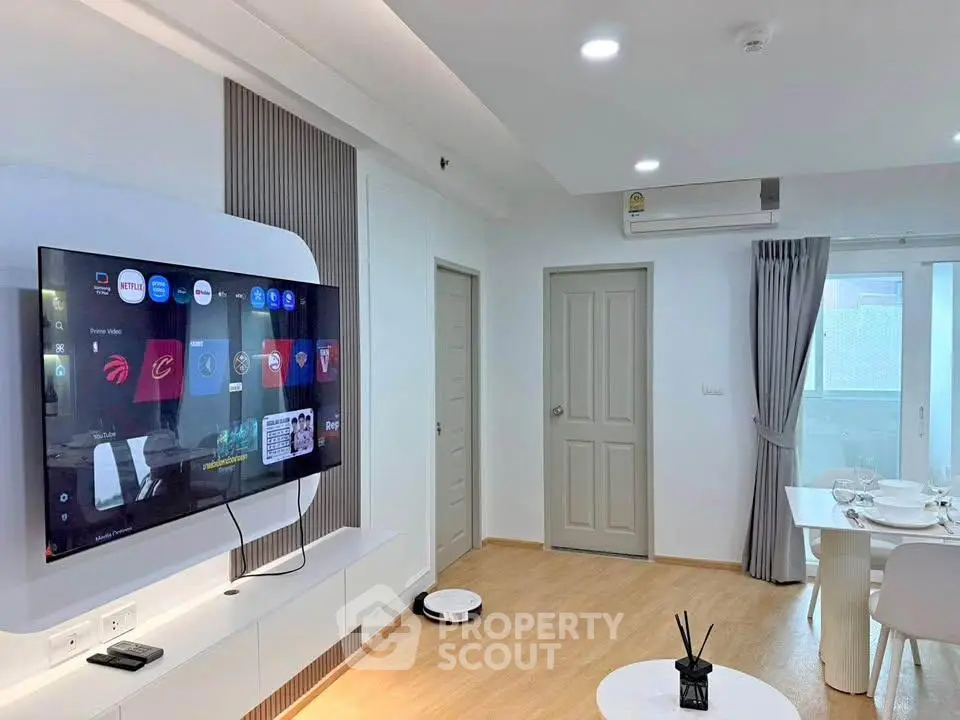Modern living room with wall-mounted TV and dining area in a bright apartment