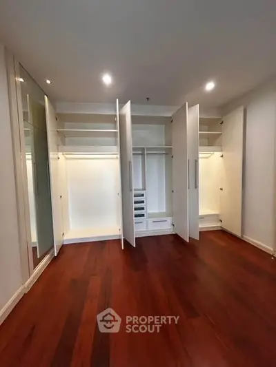 Spacious walk-in closet with elegant wooden flooring and ample storage space.