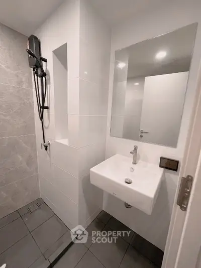 Modern bathroom with sleek design, featuring a wall-mounted sink and large mirror.