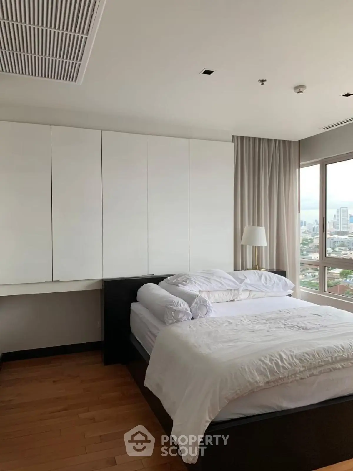 Modern bedroom with city view, featuring sleek design and natural light.