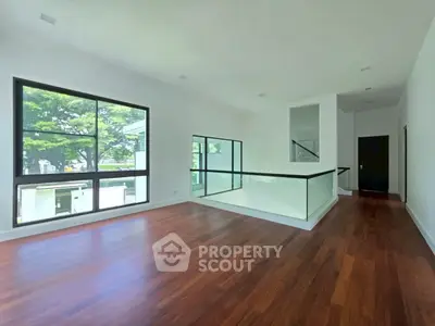 Spacious modern living room with hardwood floors and large windows offering natural light.