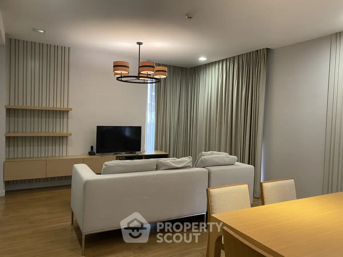 Modern living room with elegant decor and cozy seating area, featuring a stylish chandelier and natural light.