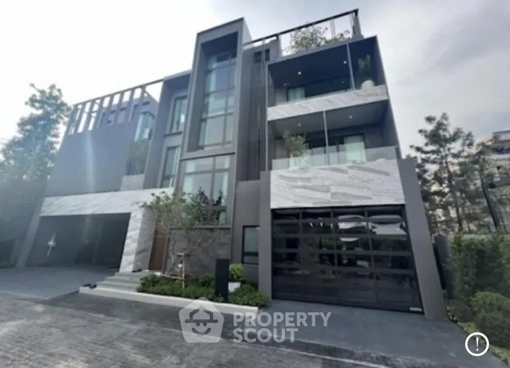 Modern multi-story building with sleek design and large windows, surrounded by greenery.