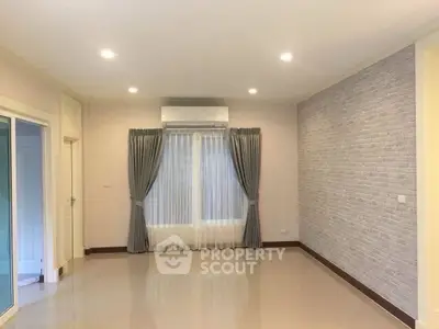 Spacious empty living room with modern brick accent wall and large window.