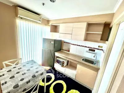 Modern kitchen with sleek cabinetry, dining area, and natural light in a cozy apartment.