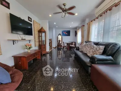 Spacious living room with elegant decor and glossy flooring, featuring a large TV and comfortable seating.