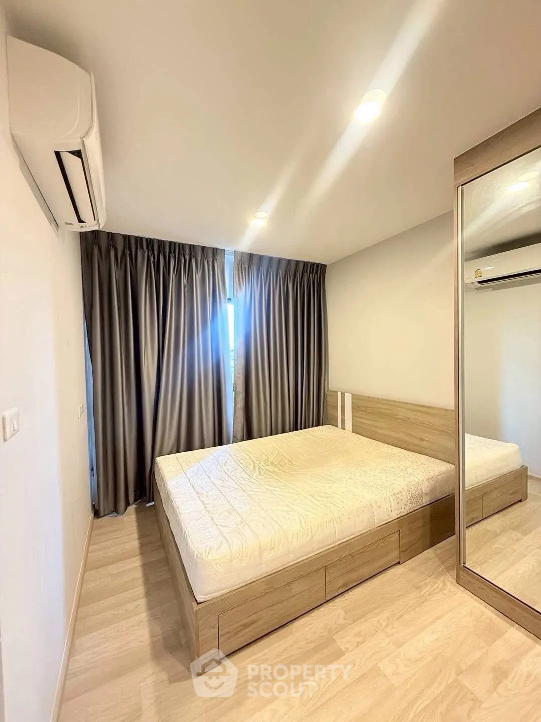 Modern bedroom with mirrored wardrobe and air conditioning, featuring sleek design and ample natural light.