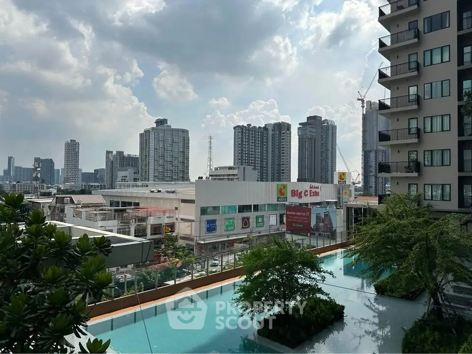 Stunning cityscape view from modern apartment balcony overlooking pool and skyline.