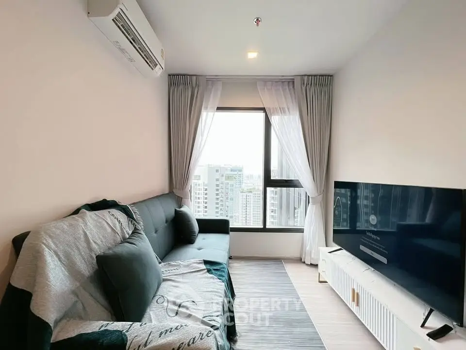 Modern living room with city view, featuring sleek furniture and large window for natural light.
