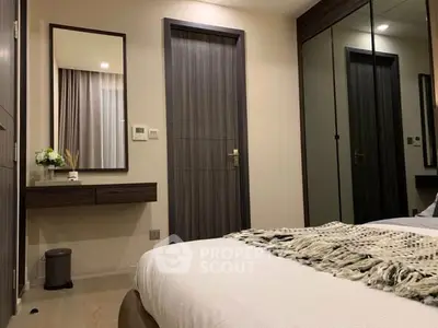 Modern bedroom with stylish decor and mirrored wardrobe in a cozy apartment.