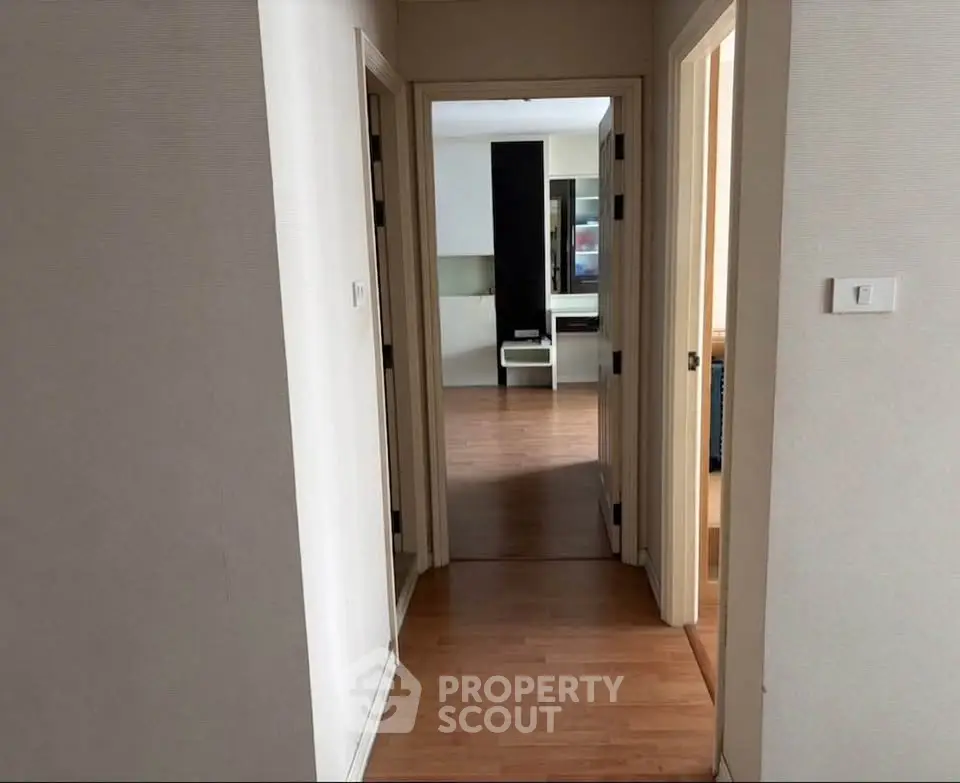 Spacious hallway leading to a modern living area with wooden flooring.