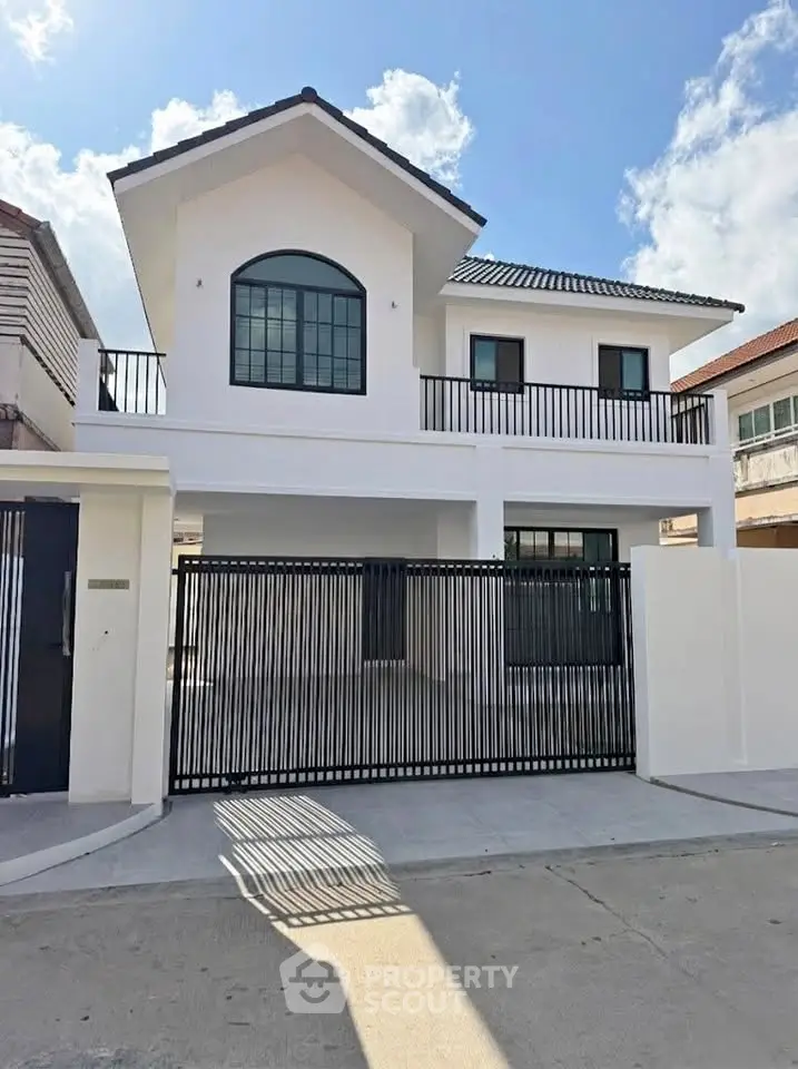 Modern two-story white house with black accents and spacious driveway under clear blue sky.