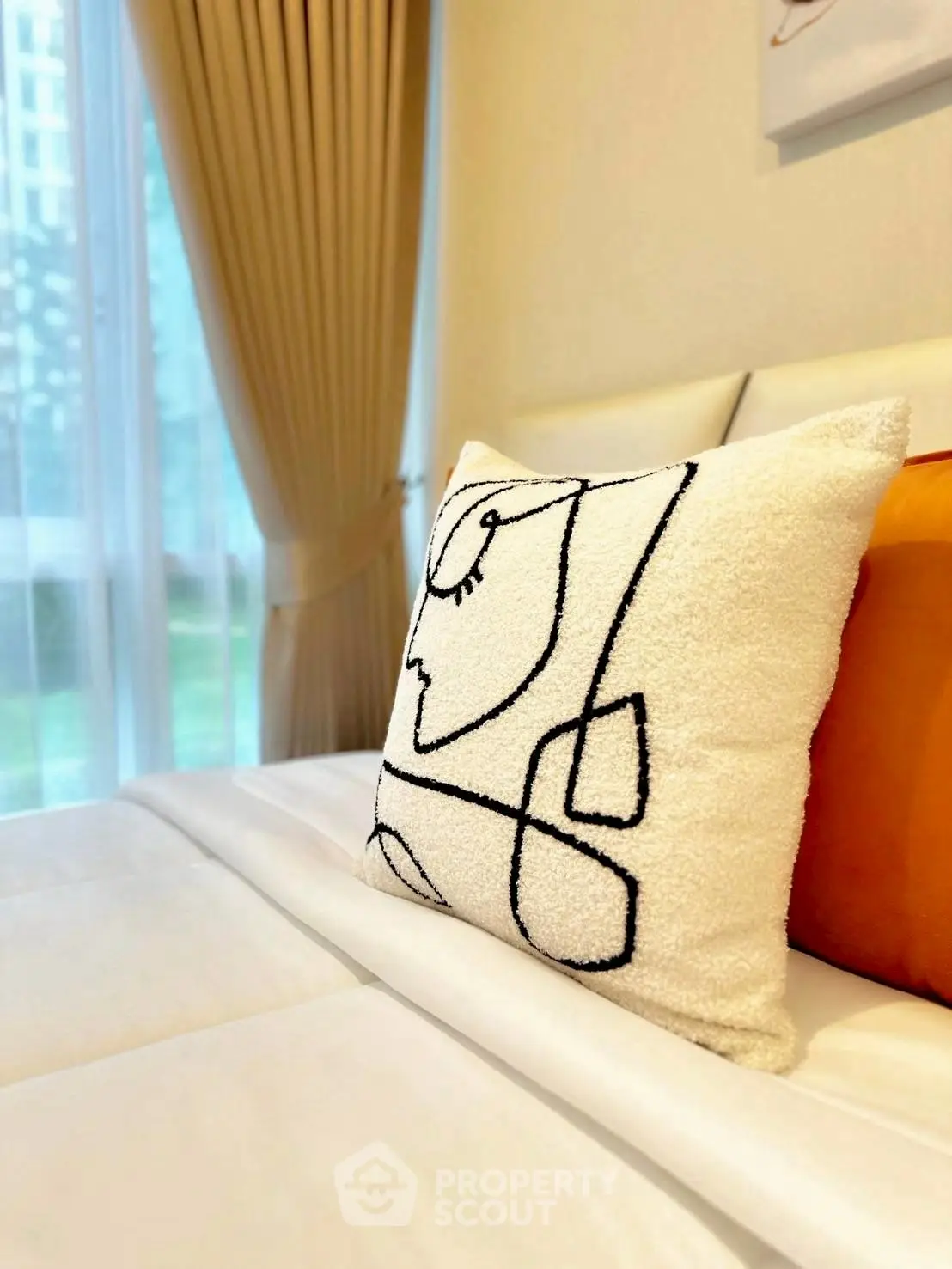 Stylish bedroom with modern art pillow and elegant curtains, perfect for a cozy retreat.