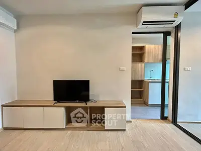 Modern living room with sleek TV stand and view into contemporary kitchen